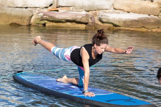 Woman in yoga pants stretching on a stand up paddle board on the lake Woman in yoga pants stretching on a stand up paddle board on the lake