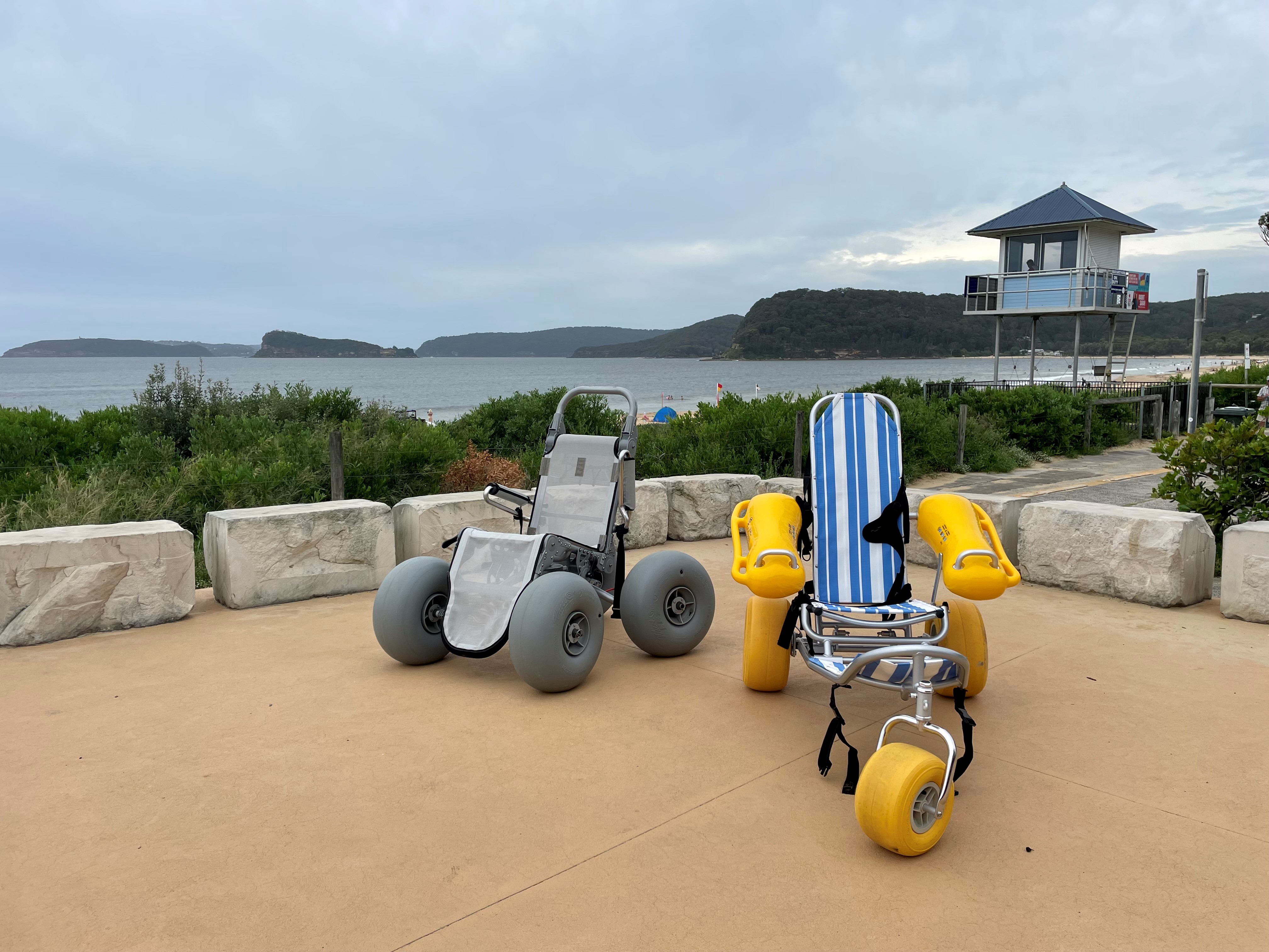 two beach whelchairs with beach in background 