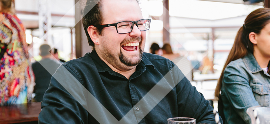 Image of man laughing in outdoor dining/bar area 