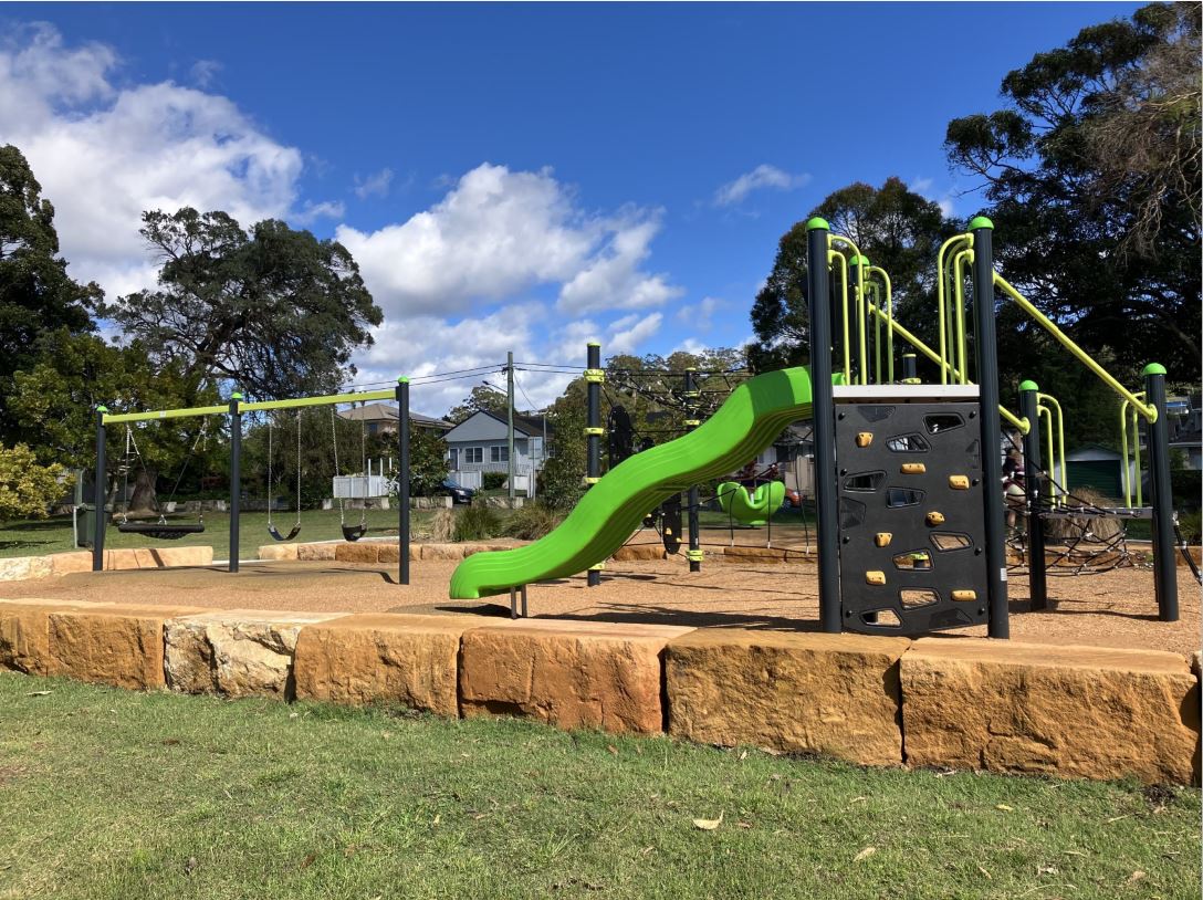 playspace in park with swings, climbing unit and slide