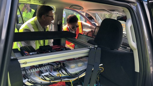 Two men with high vis vests in vehicle with electrical cords
