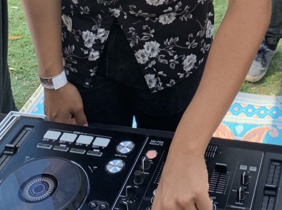 Person in black short sleeved shirt operating a DJ deck