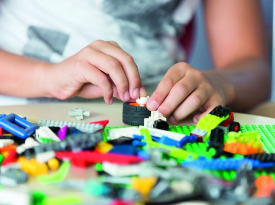 Colourful lego spread on a table and child building