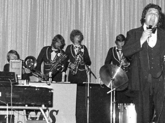 Black and white Image of Ricky May singing with band in the background