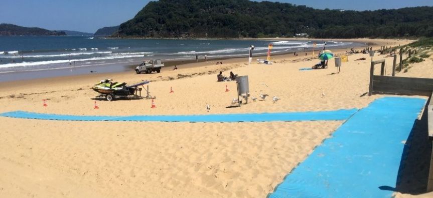 Blue beach matting rolled out across the sand at Ocean Beach. The ocean is in the background.